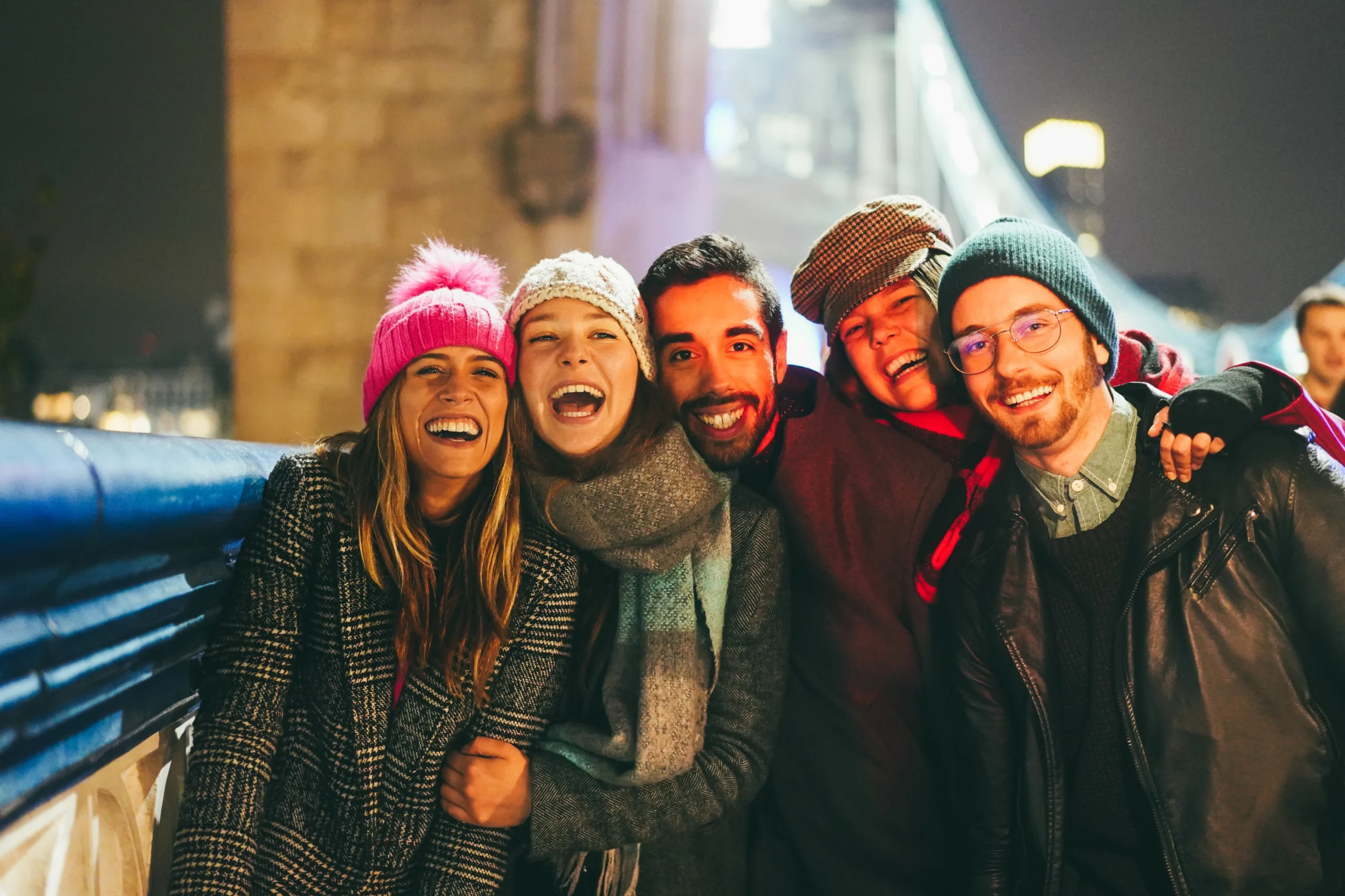 5 young adults smiling and having fun outdoors in a city